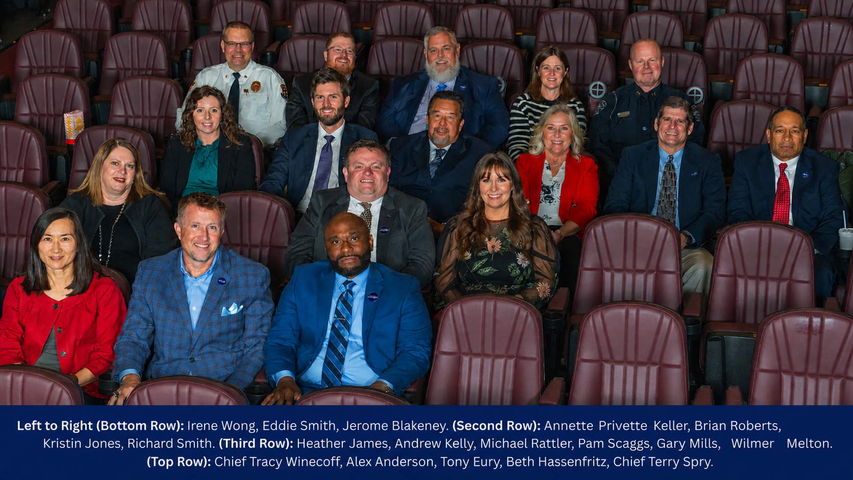 4 rows of individuals sitting in red movie theatre seats smiling for a photo 